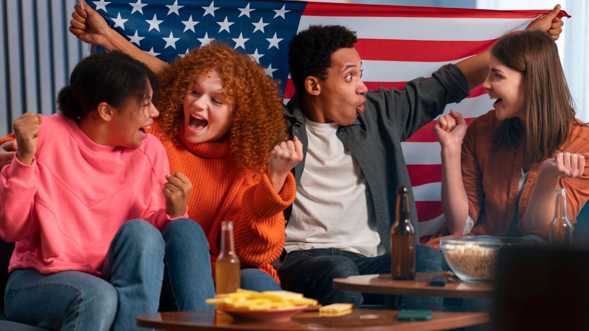 a group of friends watching television, raising the American flag